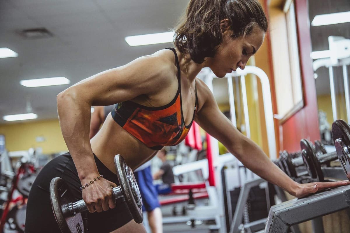 Frau trainiert Rudern mit Kurzhantel im Fitnessstudio